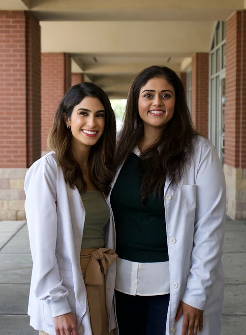Dentists Jasmin Dhanjal And Kimia Devine standing nect to each other with arms wrapped behind each other